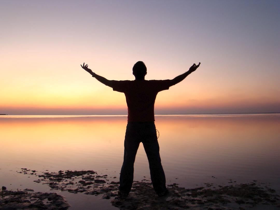 Man with his arm's outretched on the shore at sunset, Lorraine Pentello, Somatic Sex Therapy, Melbourne